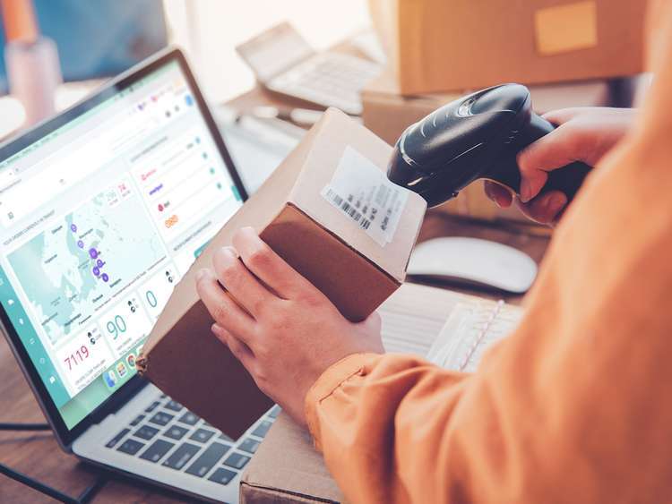 Trabalhador de um eCommerce a fazer o scan da etiquetas de envio de uma encomenda.