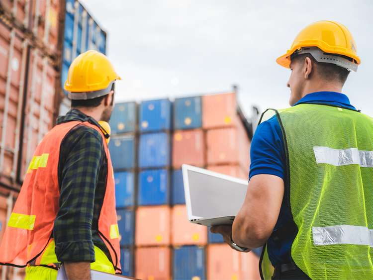 Os operadores verificam os contentores destinados à logística internacional.