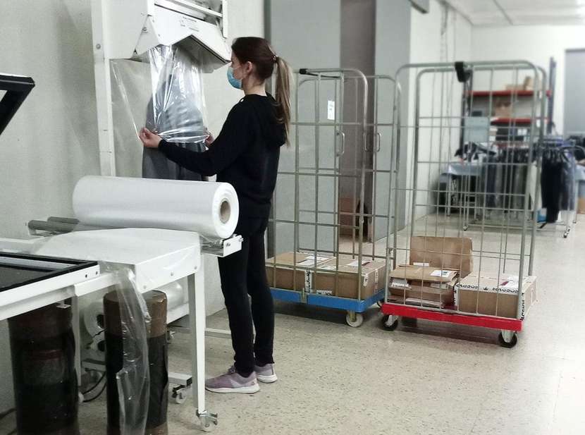 Mujer embalando un traje en un almacén de logística de un ecommerce de moda